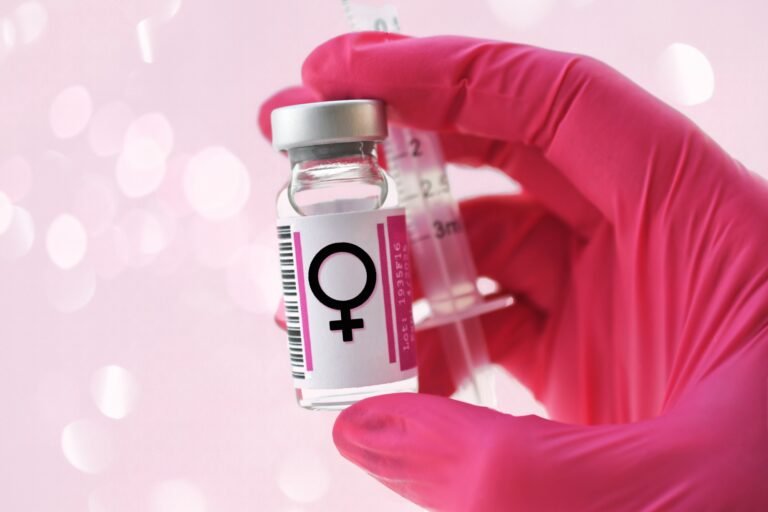 Pink gloved hand holding a vial with female symbol, hormones injections, concept hormone replacement